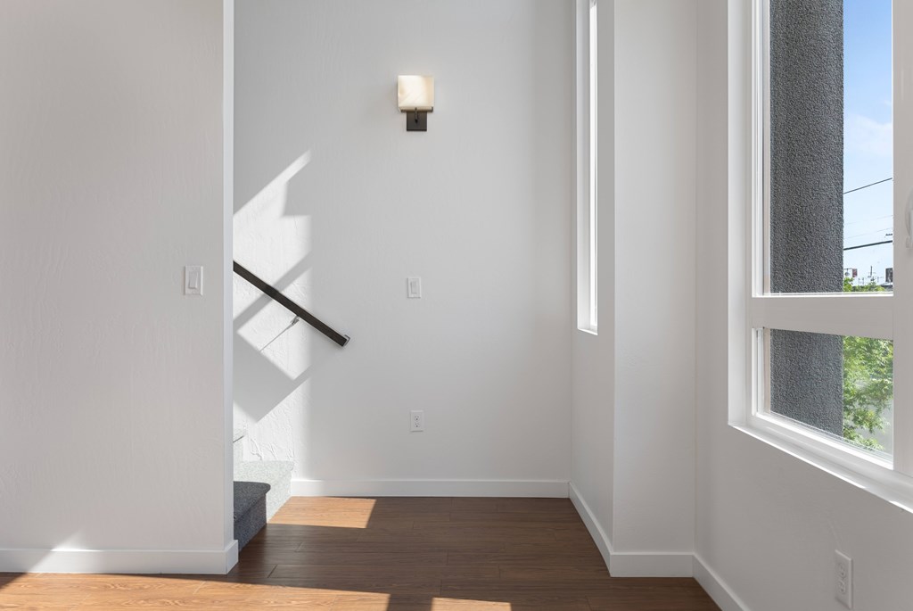 A white hallway with a light on the wall and a window on the right.